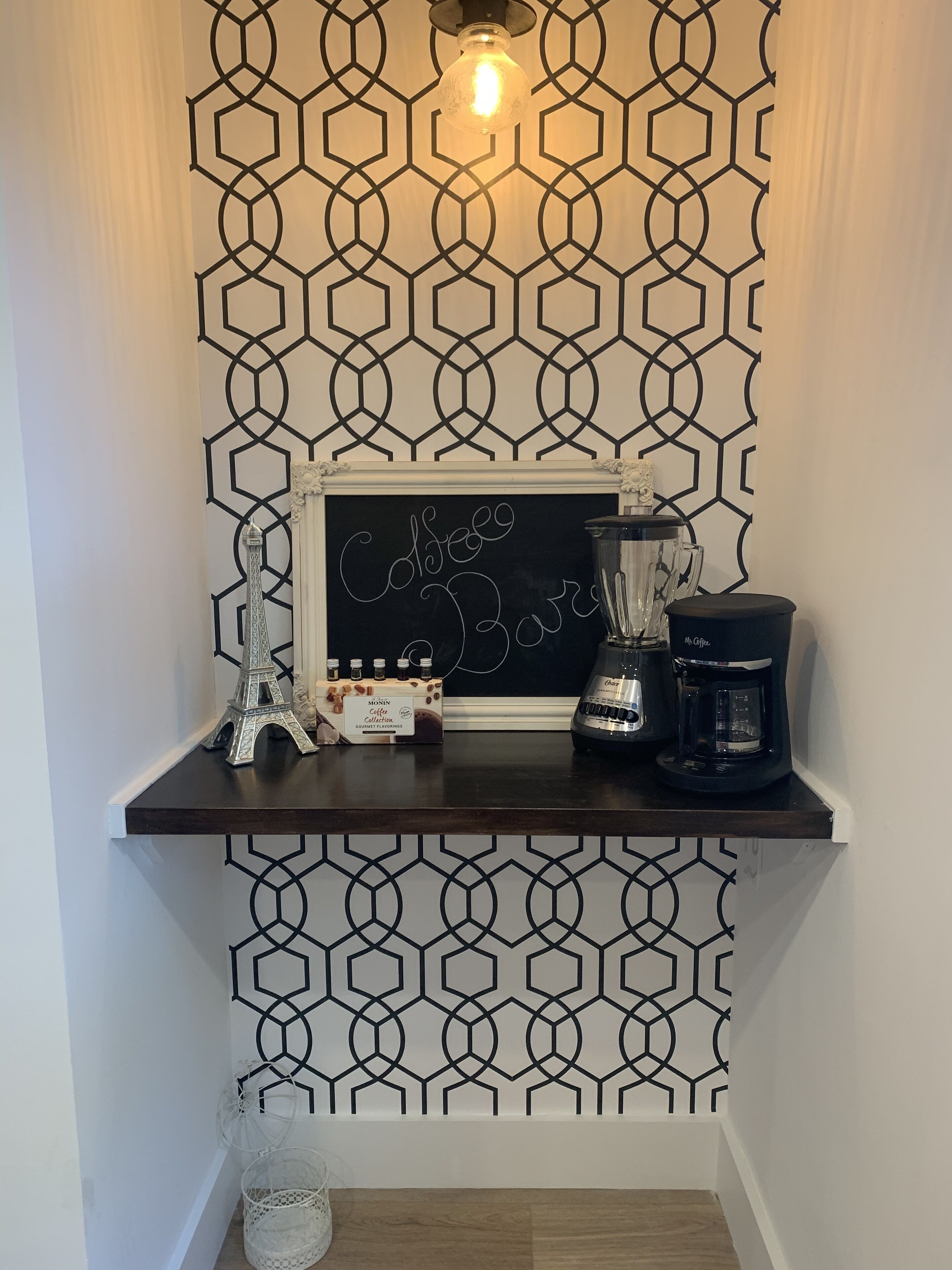 A coffee station with a chalkboard sign, a coffee maker, and a collection of coffee beans.