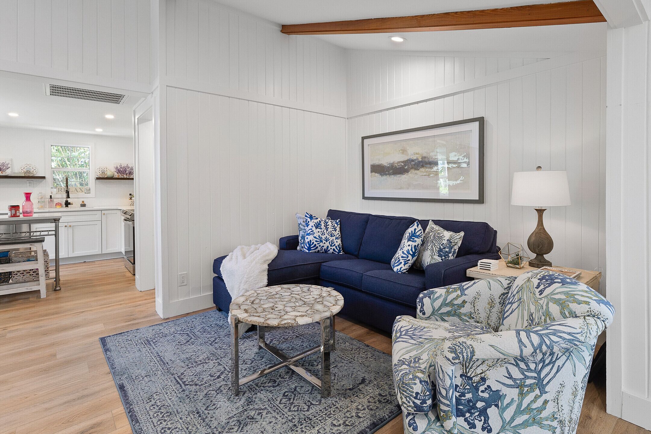 A living room with a blue sofa, patterned armchair, and a round table.