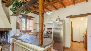 A rustic kitchen with a stone countertop, wooden beams, a stainless steel refrigerator, and a brick stove. - Villa Bellavista Large Private Pool Wifi - 3122 (Ortignano Raggiolo)