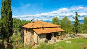 A stone house with a tiled roof, surrounded by greenery and mountains in the background. - Villa Bellavista Large Private Pool Wifi - 3122 (Ortignano Raggiolo)