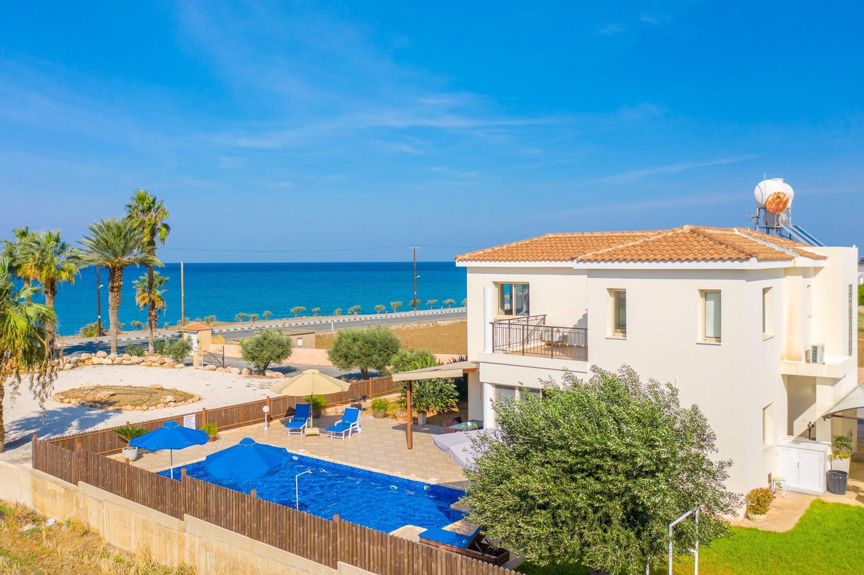 A two-story building with a swimming pool and a view of the sea.