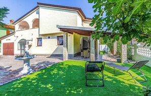 Ein Haus mit Terrasse, einer Statue und einem Trampolin.