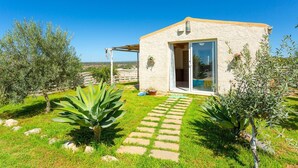 A small, single-story building with a stone facade, a glass door, and a covered patio area.
