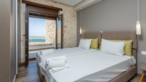 A hotel room with a large bed, a stone wall, and a view of the sea. - Villa Lulla Large Heated Private Pool Sea Views A C Wifi - 3200 (Chania)