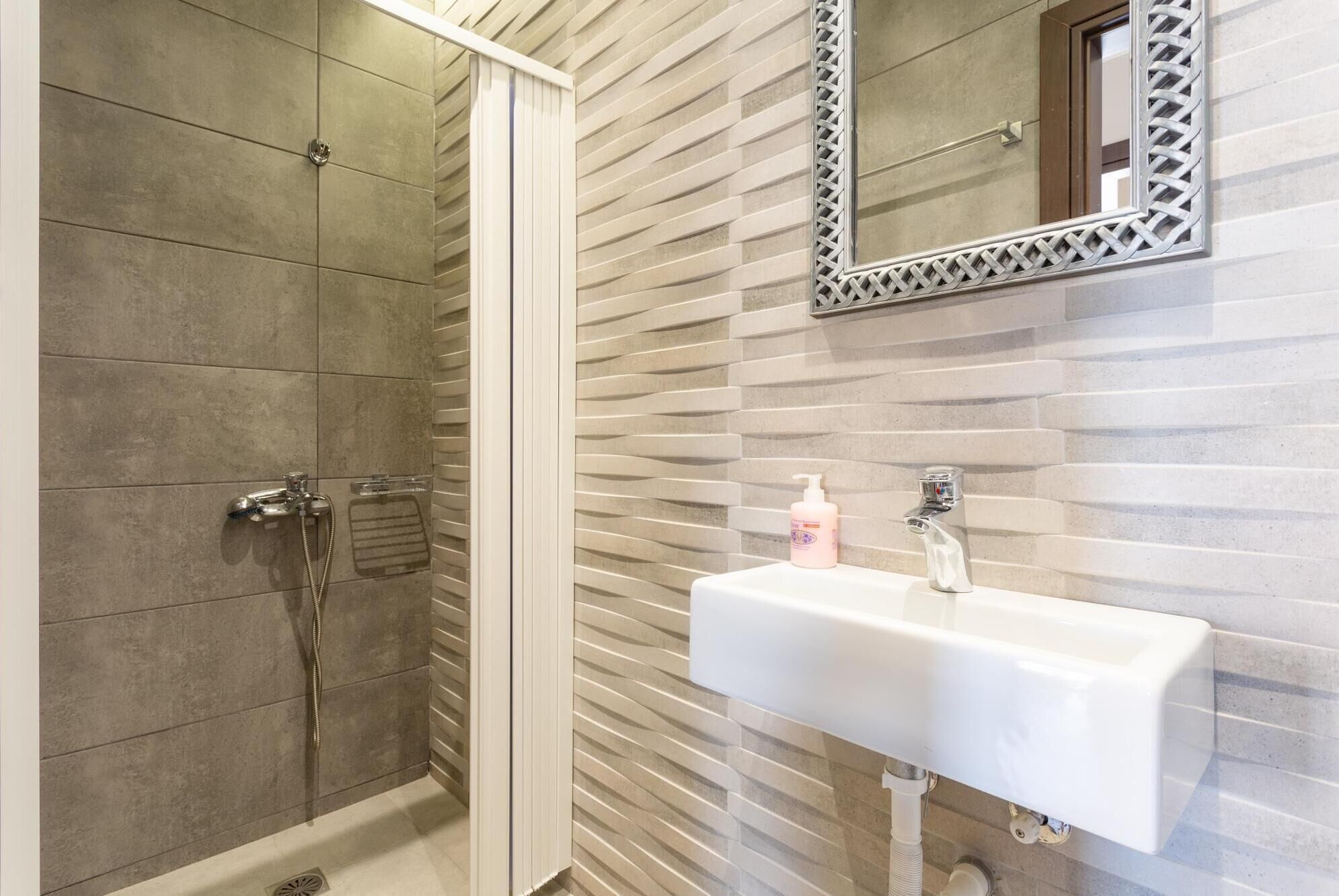 Une salle de bain avec une douche, un lavabo et un miroir.