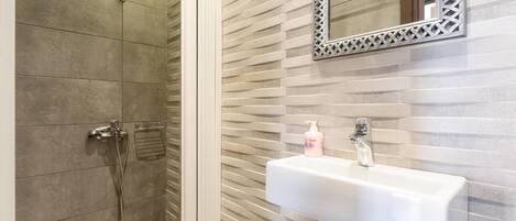 Une salle de bain avec une douche, un lavabo et un miroir.
