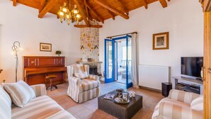 Una sala de estar acogedora con chimenea, sofás a rayas, un comedor con piano y televisión.