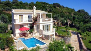 Ein zweistöckiges Haus mit Swimmingpool, Sitzgelegenheiten im Freien und einem Garten.