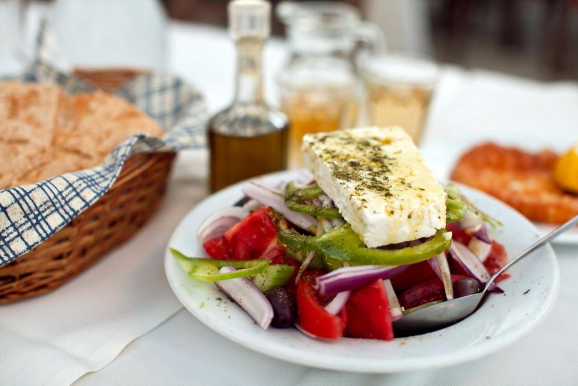 Un plato de pescado con verduras y una porción de queso sobre un plato blanco.