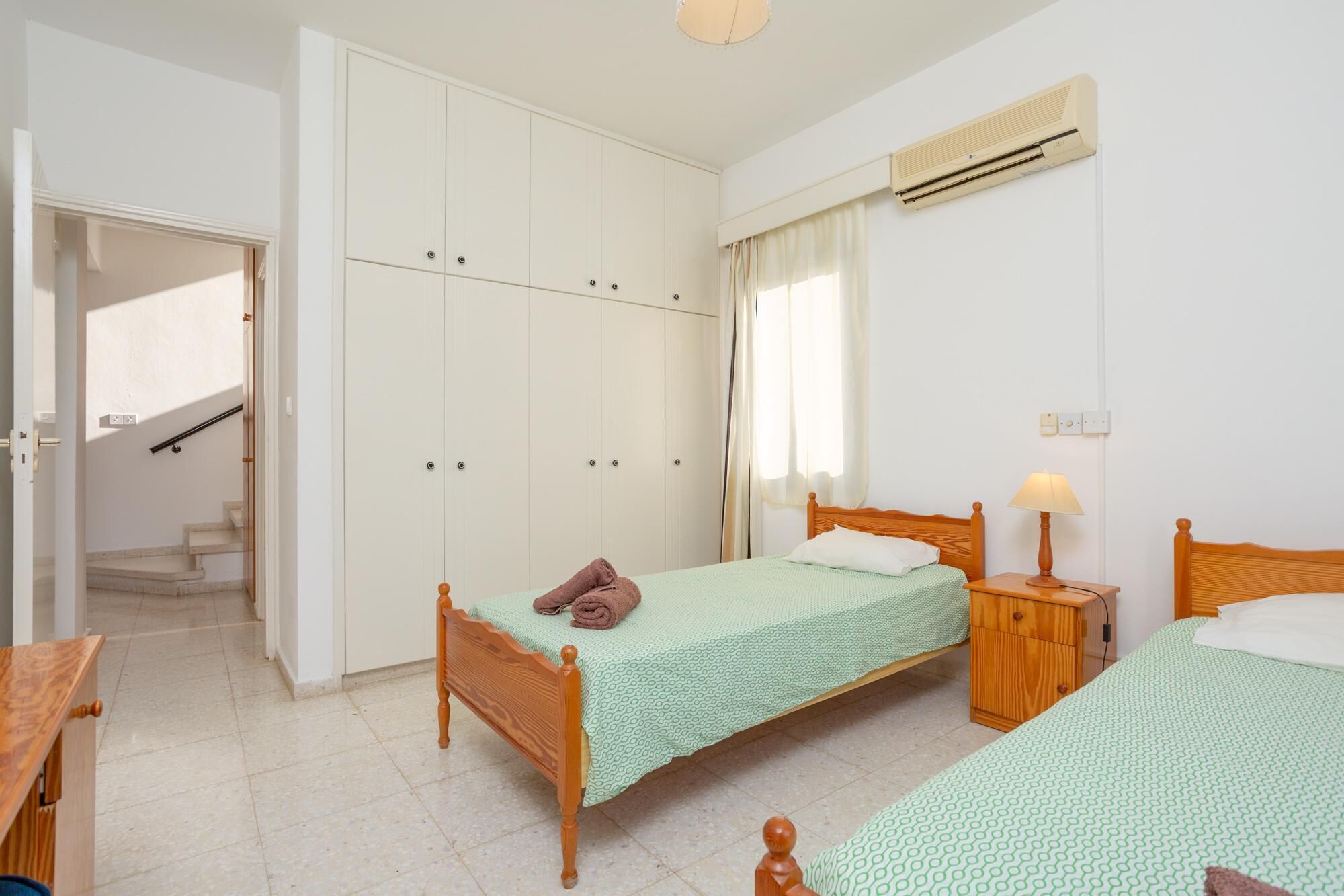 A bedroom with a bed, a nightstand, a wardrobe, and a staircase leading to another room.