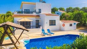 Una casa de dos pisos con piscina, balcón y una pequeña construcción adosada.