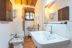 Une salle de bain avec une baignoire, deux toilettes, un lavabo et un miroir.
