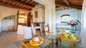 Un coin repas avec une table en verre, des chaises et un panier de fruits.