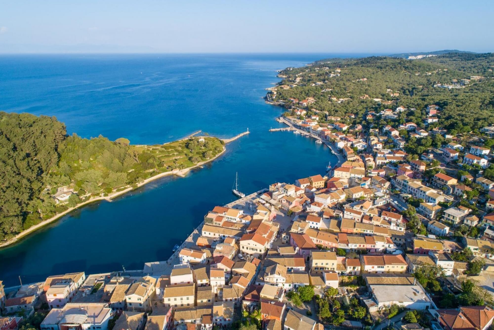 Vue aérienne d’une ville côtière avec un ensemble dense de bâtiments, un port de plaisance et une petite péninsule verdoyante.
