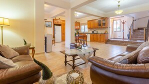A spacious living room with a fireplace, leather sofas, and a dining area with wooden cabinets and a kitchen in the background.