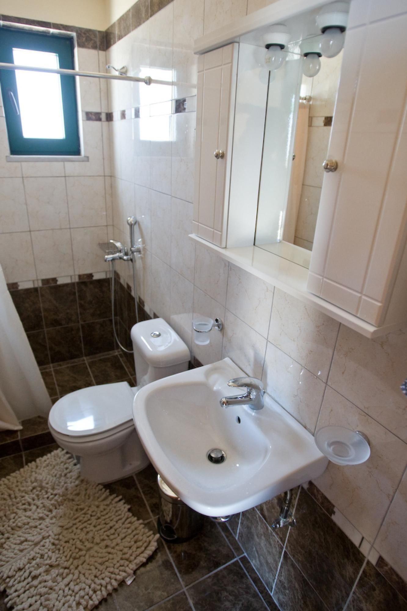 Une salle de bain comprenant des toilettes, un bidet, un lavabo et une douche.