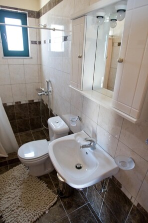 Een badkamer met toilet, bidet, wastafel en douche.