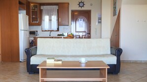 Ein Wohnzimmer mit einer Couch, einem Couchtisch und einer Küche im Hintergrund.