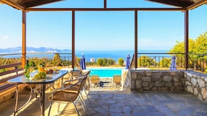 Ein überdachter Außenbereich mit Pool, Steinmauern und Blick auf das Meer.