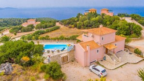 A two-story house with a swimming pool, surrounded by trees and hills. - Villa Yeraki Large Private Pool Sea Views A C Wifi - 981 (Kefalonia)