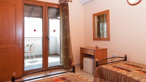 A bedroom with a bed, a wooden wardrobe, a small desk, a mirror, and a sliding glass door leading to a balcony. - Villa Yeraki Large Private Pool Sea Views A C Wifi - 981 (Kefalonia)