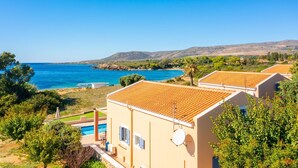 A coastal villa with a swimming pool, terracotta roofs, and a view of the sea and hills. - Antigoni Beach House Large Private Pool Walk to Beach Sea Views A C Wifi Car Not Required - 1012 (Kefalonia)