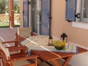 A wooden table with a floral tablecloth, a bowl of fruit, and two lanterns on a balcony with blue shutters. - Nafsika Beach House Large Private Pool Walk to Beach Sea Views A C Wifi Car Not Required - 1880 (Kefalonia)