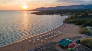 A beach with rows of umbrellas and a small building, likely a beach hut, near the water. - Nafsika Beach House Large Private Pool Walk to Beach Sea Views A C Wifi Car Not Required - 1880 (Kefalonia)