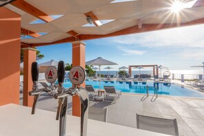 A poolside area with a bar, lounge chairs, umbrellas, and a view of the sea. - Nafsika Beach House Large Private Pool Walk to Beach Sea Views A C Wifi Car Not Required - 1880 (Kefalonia)