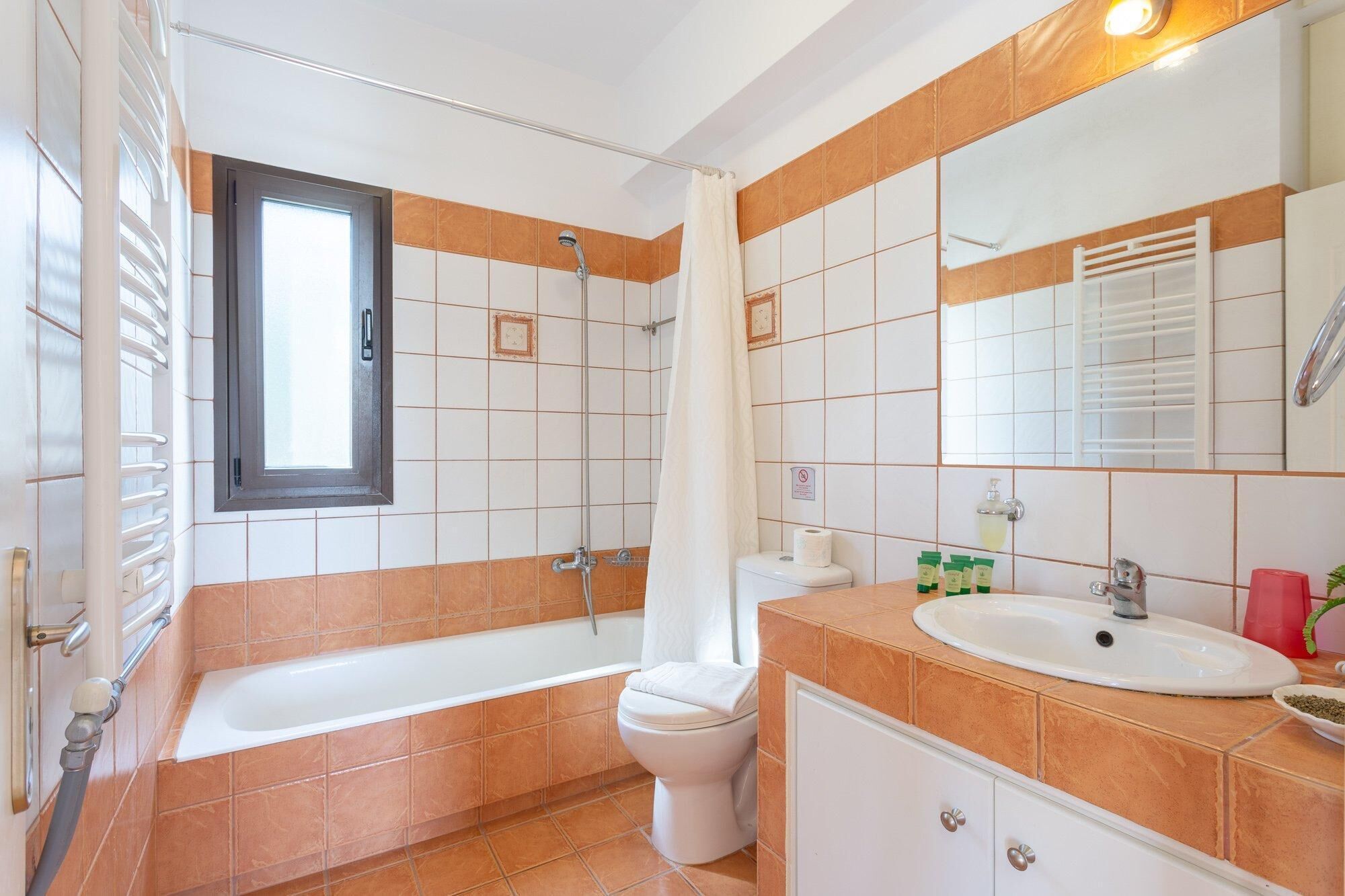 A bathroom with a bathtub, toilet, sink, and a large mirror.