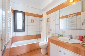 A bathroom with a bathtub, toilet, sink, and a large mirror.