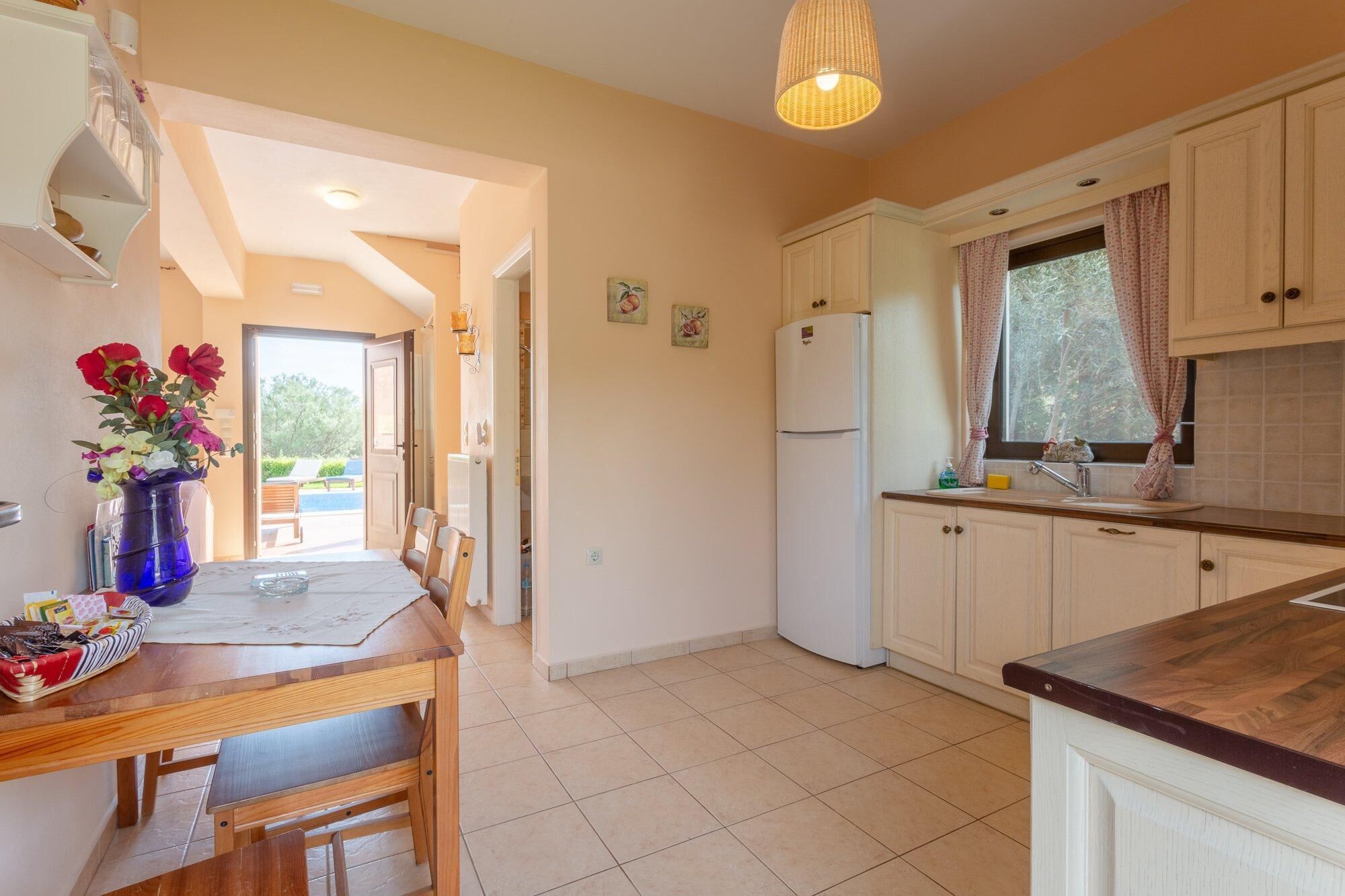 A kitchen with white cabinets, a wooden countertop, and a dining area with a table and chairs.