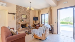 A living room with a fireplace, a television, and a sofa. - Villa Eufrosini Large Private Pool Walk to Beach Sea Views A C Wifi Car Not Required - 2301 (Kefalonia)