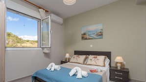 A bedroom with a bed, two bedside tables with lamps, a window with curtains, and a painting on the wall. - Vatsa Beach Villa Large Private Pool Walk to Beach Sea Views A C Wifi - 3021 (Kefalonia)