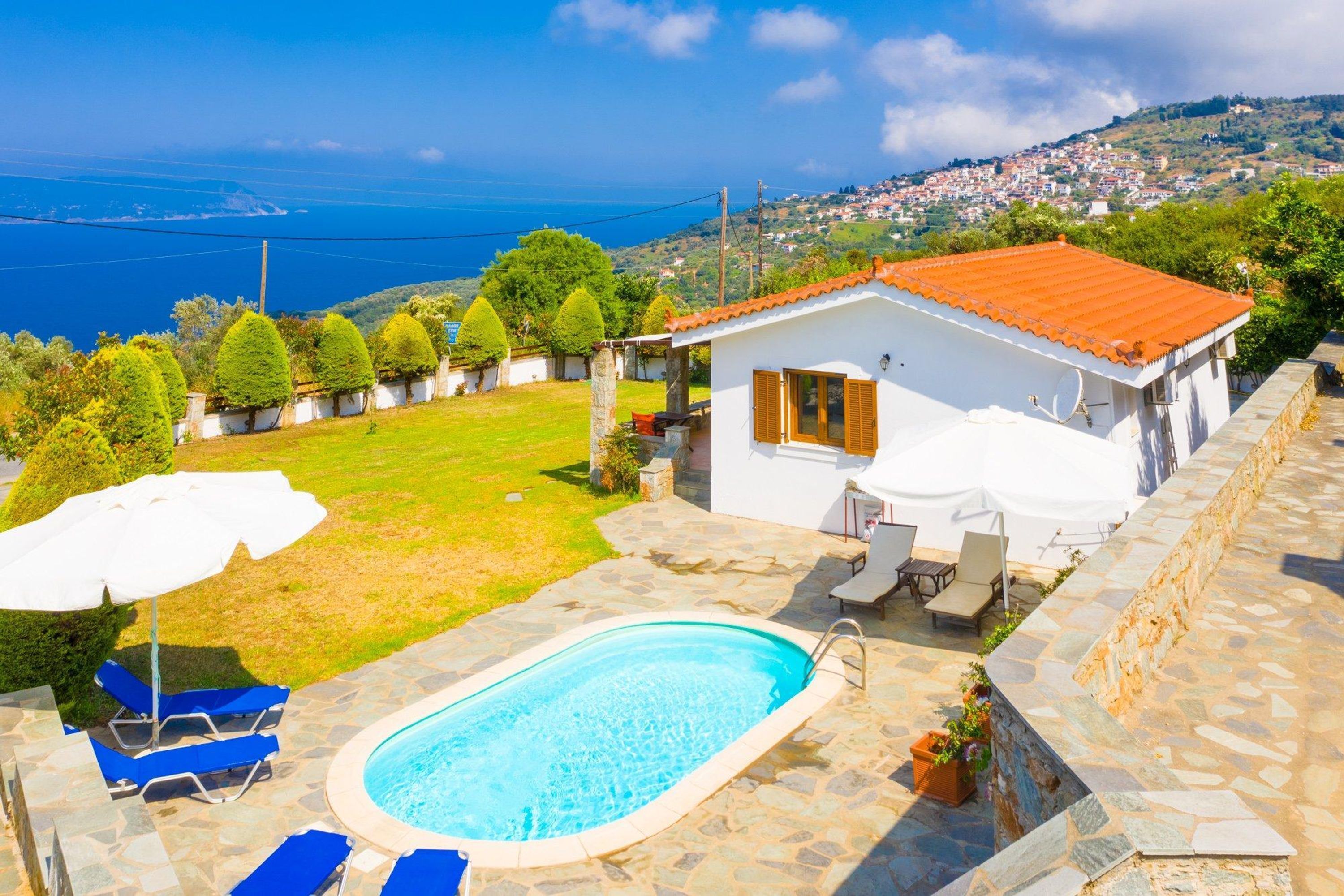 Une villa blanche dotée d’une piscine, d’un espace salon extérieur et offrant une vue sur la mer et la ville.