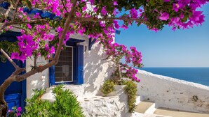A white building with blue shutters and a stone pathway leading to a door.
