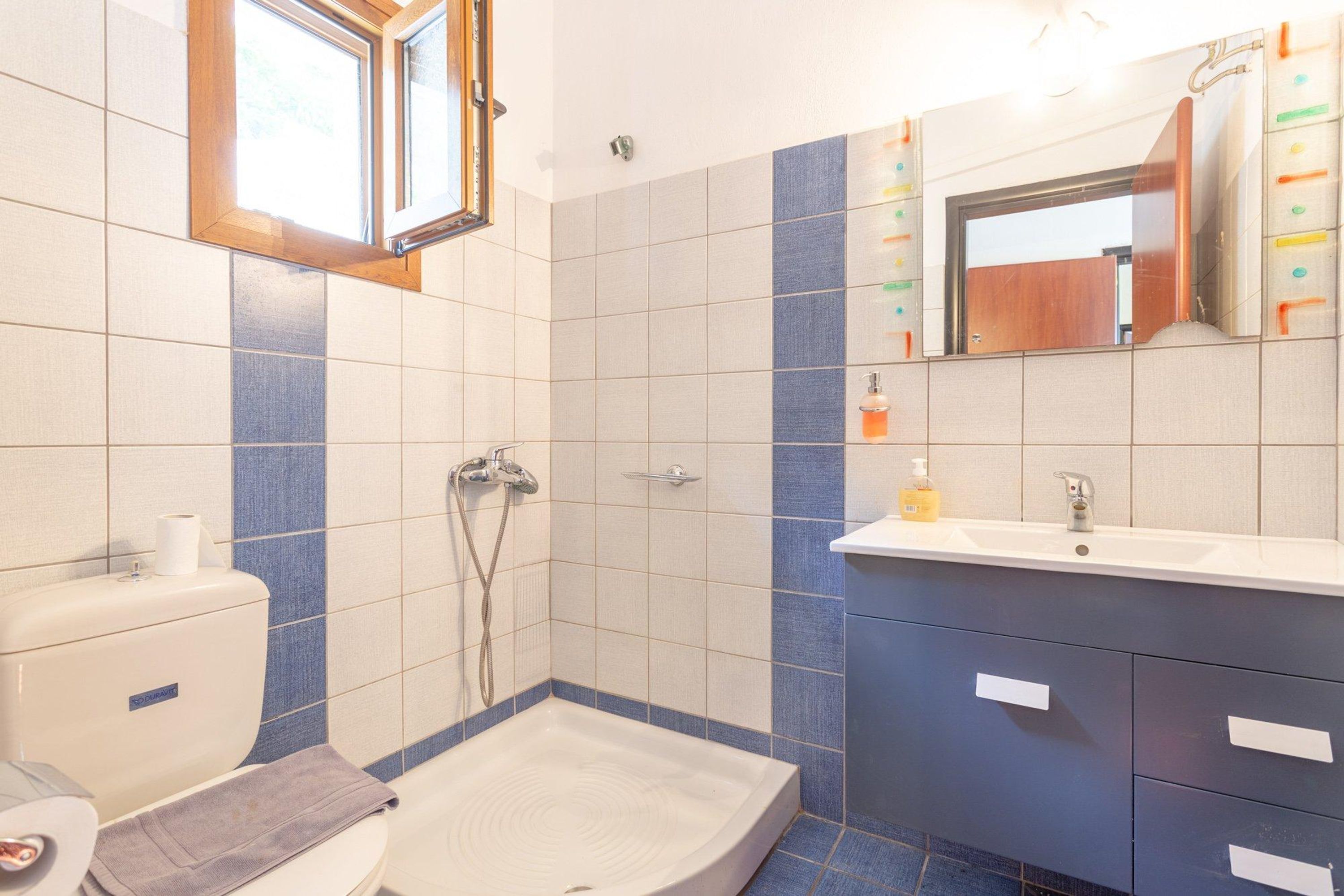 A bathroom with a shower, toilet, sink, and mirror.