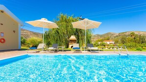 Ein Swimmingpool mit klarem, blauem Wasser, umgeben von Liegestühlen und Sonnenschirmen.