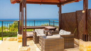 A covered outdoor seating area with wicker furniture and a view of the ocean. - Villa Minoas Large Private Pool Walk to Beach Sea Views A C Wifi Eco-friendly - 2565 (Argaka)