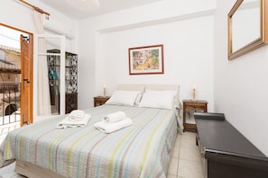 Um quarto com uma cama, duas mesas de cabeceira com abajures, um guarda-roupa de madeira e um quadro na parede.