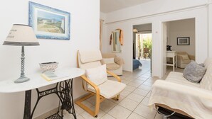 A cozy living room with a table, chairs, and a sofa. There is a painting on the wall and a lamp on the table. - Anna Apartment Walk to Beach A C Wifi Car Not Required - 2451 (Corfu)