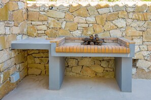 A stone wall with a built-in bench and a fire pit.