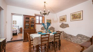 A dining area with a table set for four, surrounded by wooden chairs. A chandelier hangs from the ceiling, and there are framed pictures on the wall. - Villa Mealli Large Private Pool Wifi - 3445 (San Casciano dei Bagni)
