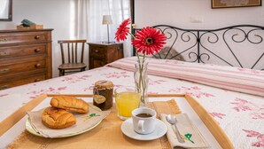 A breakfast tray with bread, jam, a cup of coffee, and a glass of juice on a bed with a floral bedspread. - Villa Mealli Large Private Pool Wifi - 3445 (San Casciano dei Bagni)