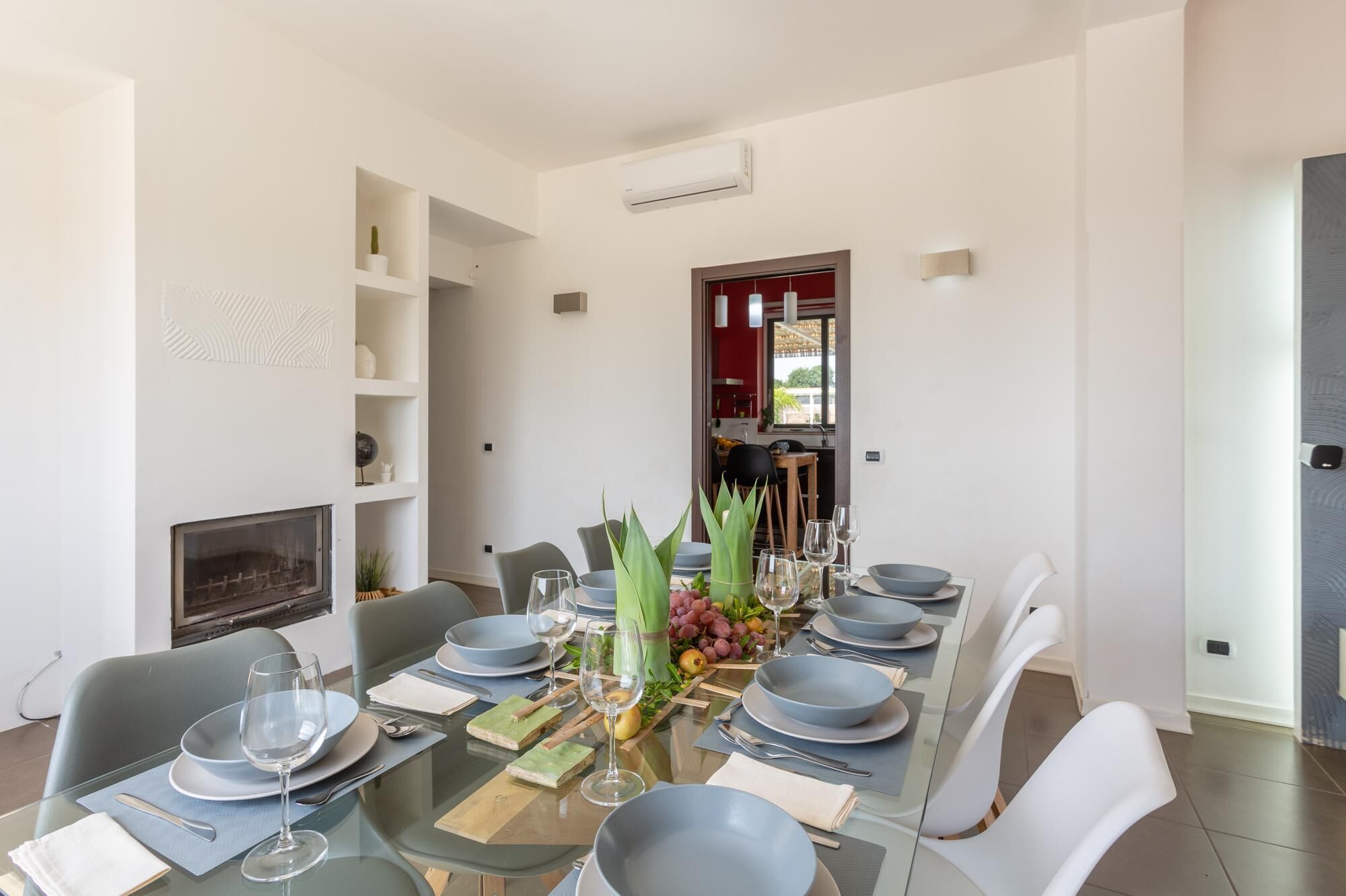 Un espace repas avec une table en verre, des chaises blanches et un aménagement intérieur moderne.