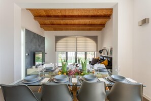 Enjoy meals with family and friends at this dining area, featuring a glass-top table for six and a comfortable leather sofa.