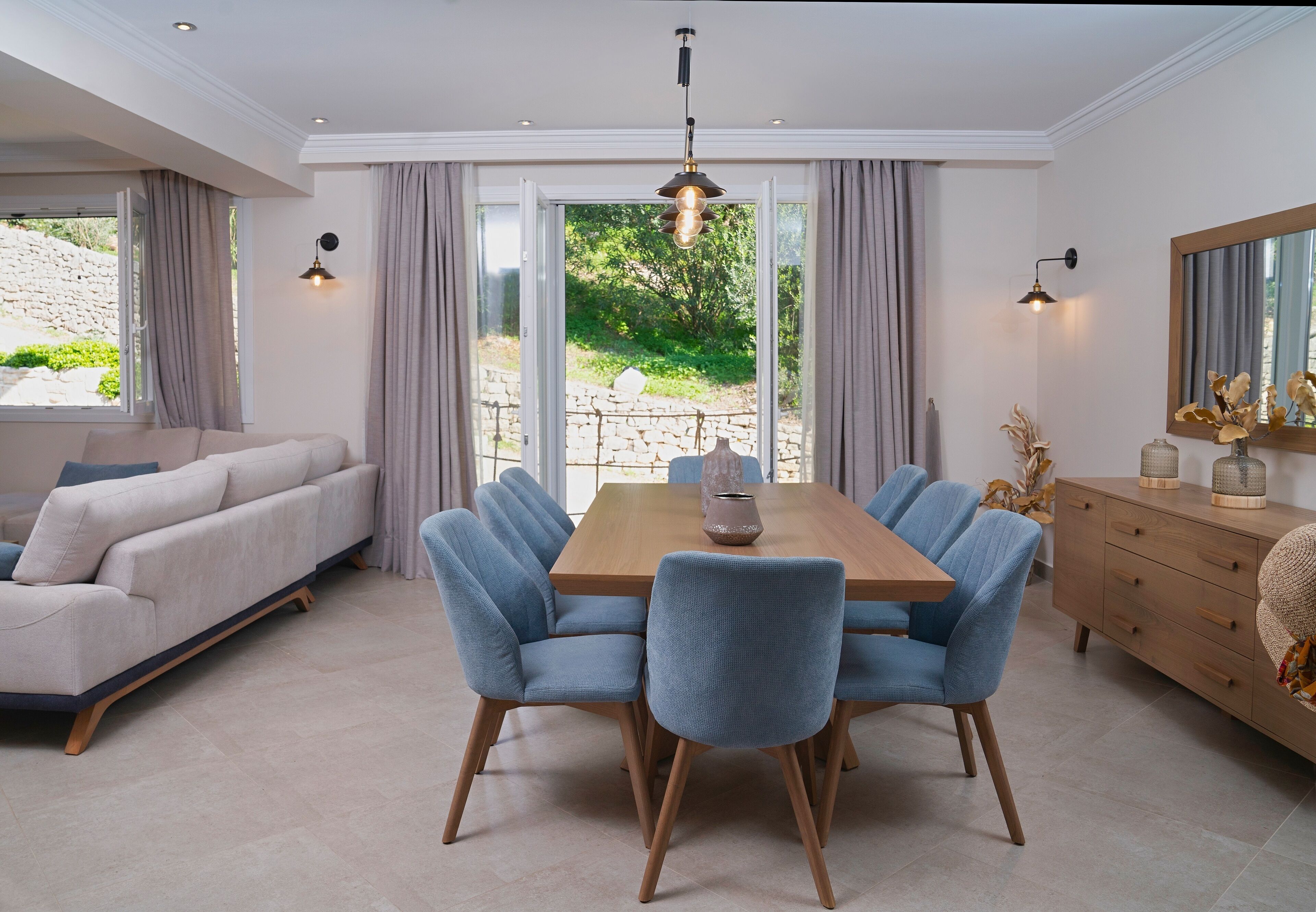 A dining area with a wooden table, six blue chairs, a beige sofa, and a wooden cabinet.