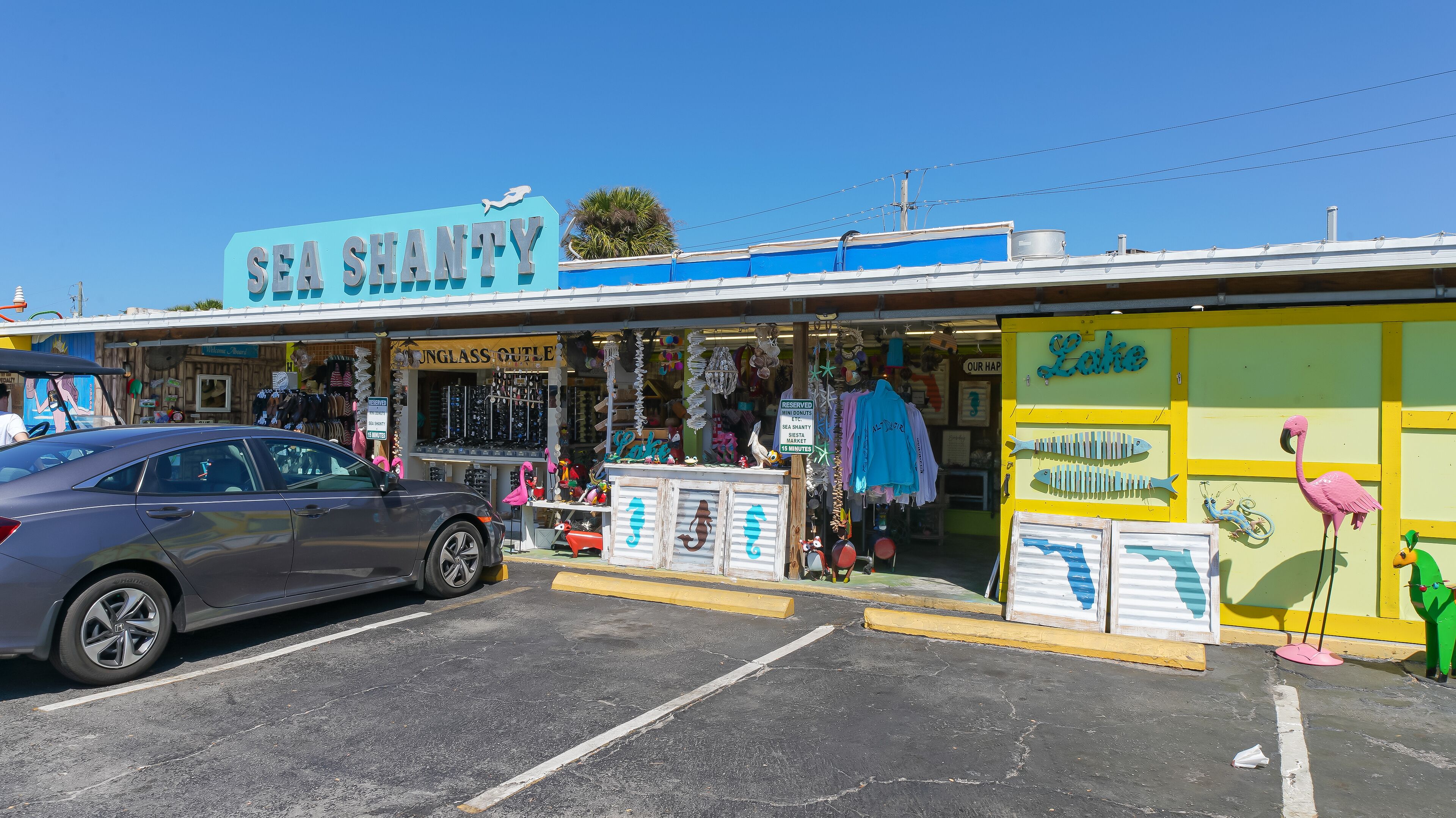 A storefront with a sign reading "SEA SHANTY" and various items for sale, including sunglasses and beachwear.
