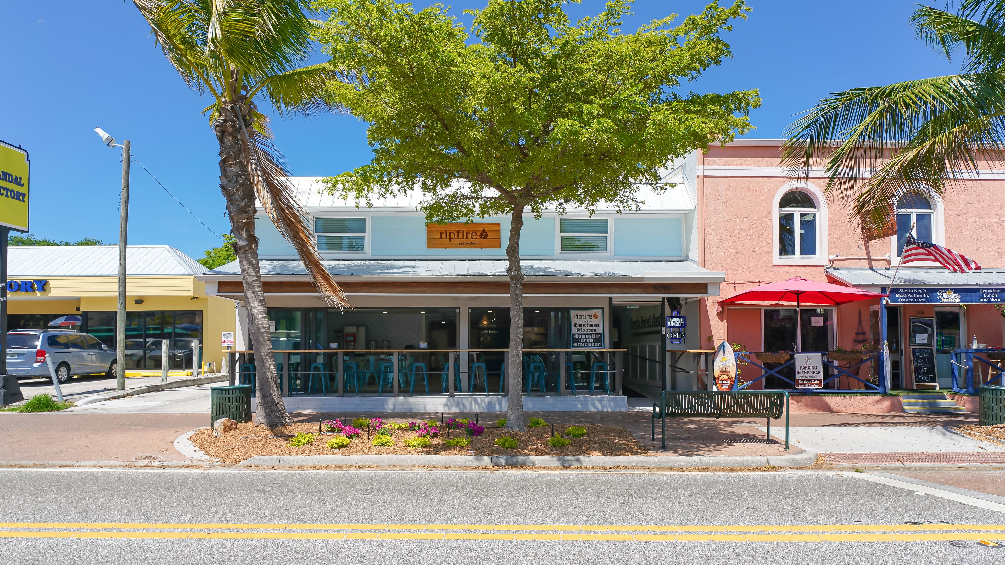 A street view with a restaurant named 'Ripfire Pizza & Bar' and a 'Siesta Key's Miami Key's French Cafe' across the street.