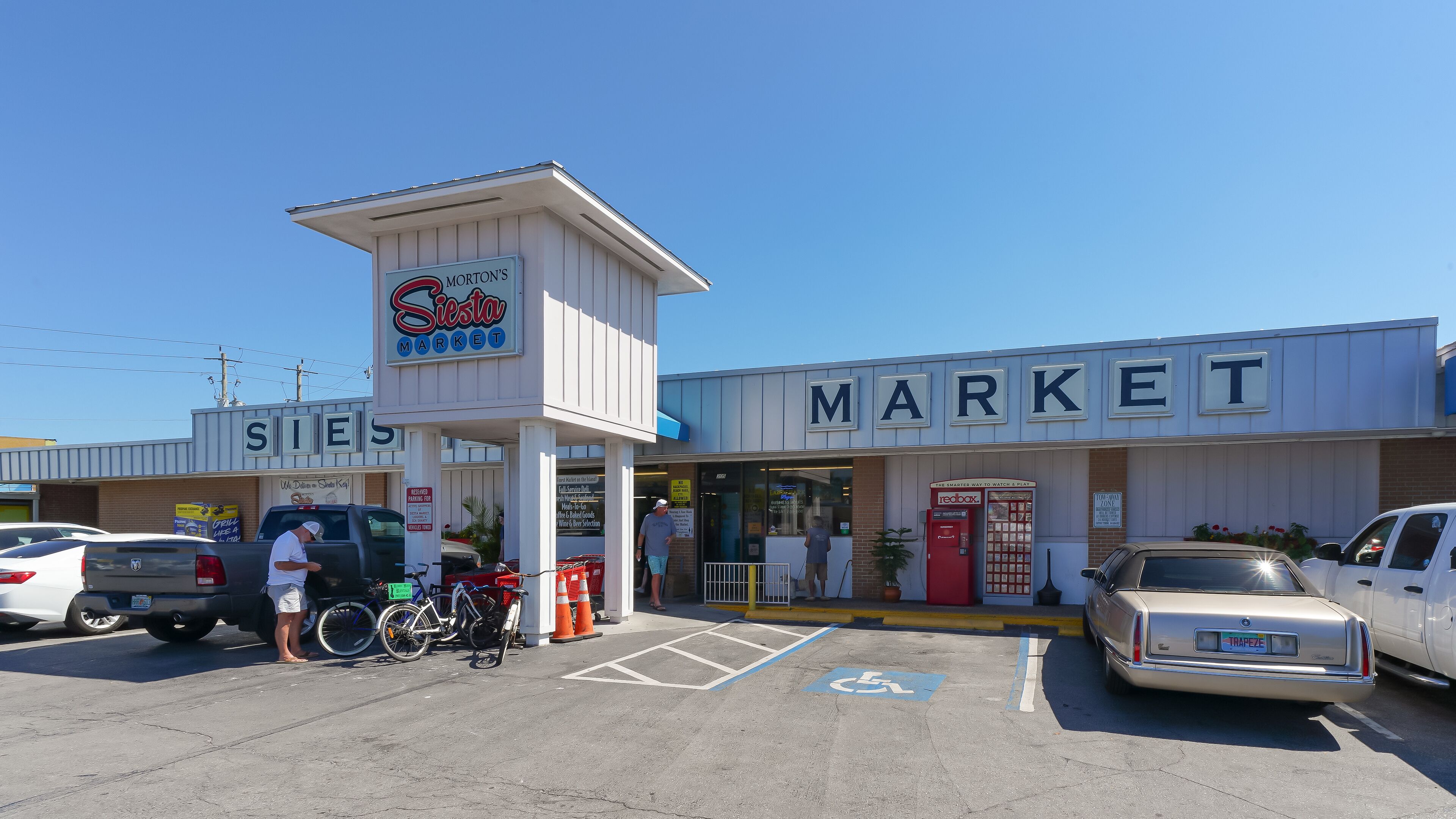 A market with a sign for Morton's Market, a parking lot with cars and bicycles, and a red mailbox.